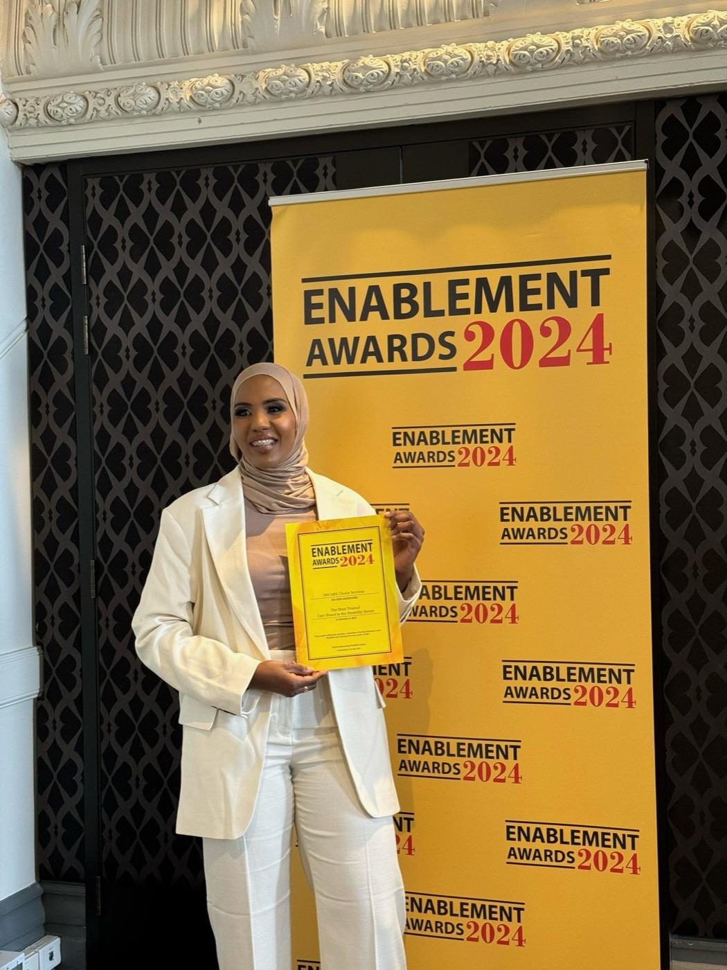 MiCare Choice Services CEO holding the Enablement Awards 2024 certificate naming MiCare the Most Trusted Care Brand in the Disability Sector
